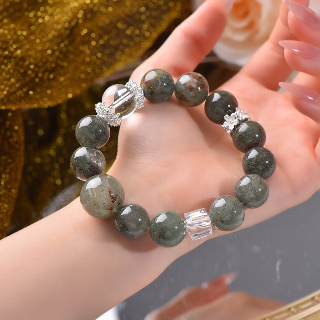 Career promotion energy bracelet held in a woman’s hand showing large green beads and clear quartz accents
