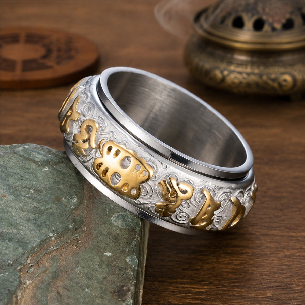 Close-up of a silver Taoist protection spinner ring with raised gold-tone rune and talisman details.