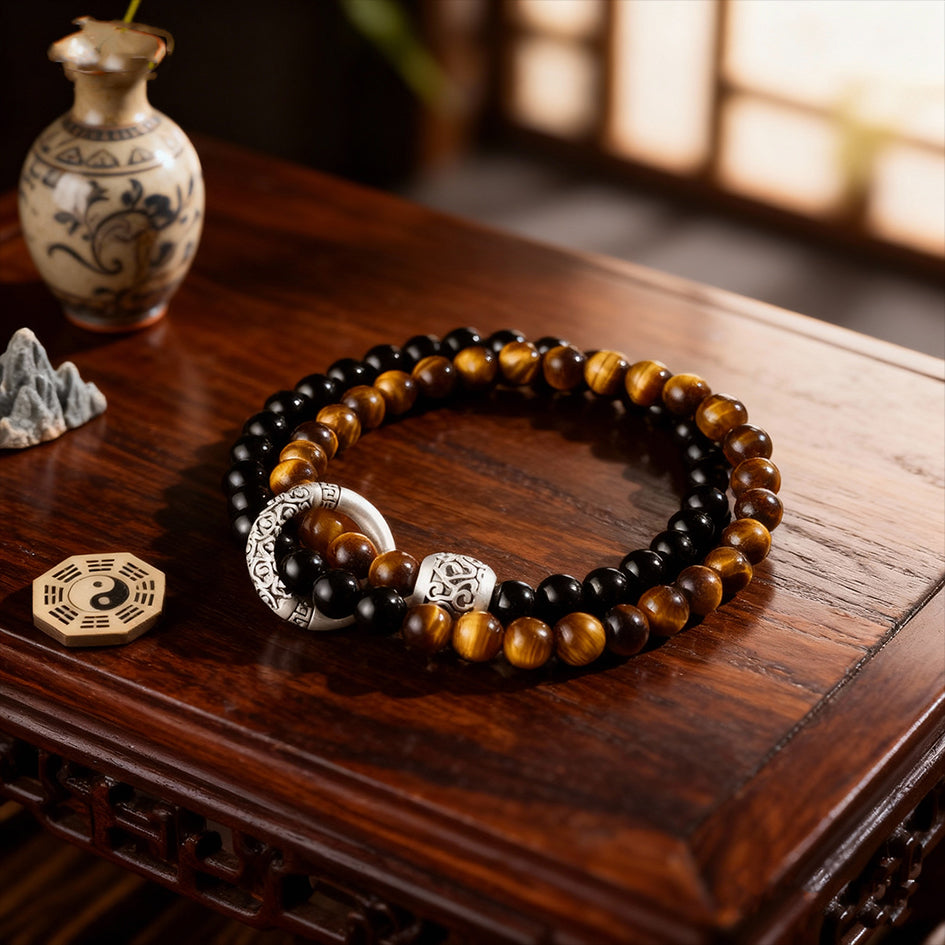 Feng Shui protection bracelet displayed on table showing full structure with hollow circle design and dual stone energy combination of Black Obsidian and Tiger Eye Stone