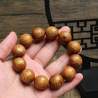 Close-up of a hand holding a thunderstruck wood bracelet engraved with Five Thunders talisman symbols and a Tai Chi bead