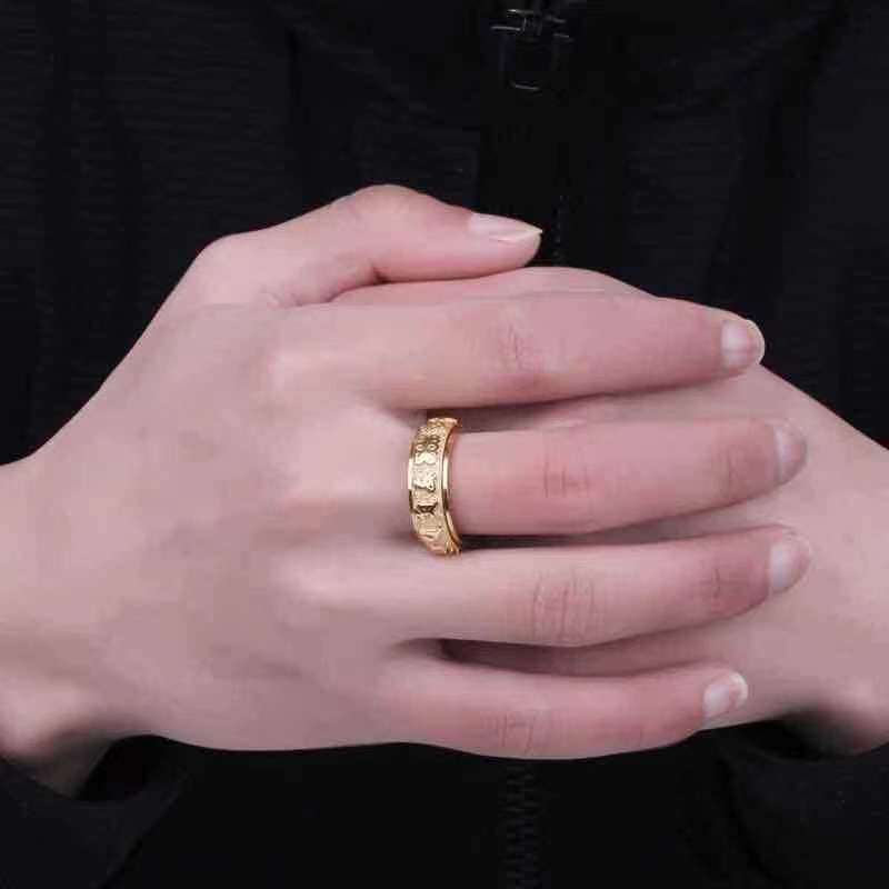 Person wearing a gold-tone Taoist protection spinner ring with engraved rune details.