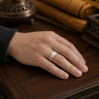 Male hand wearing a handcrafted silver Taoist protection ring with hidden inner talisman engravings