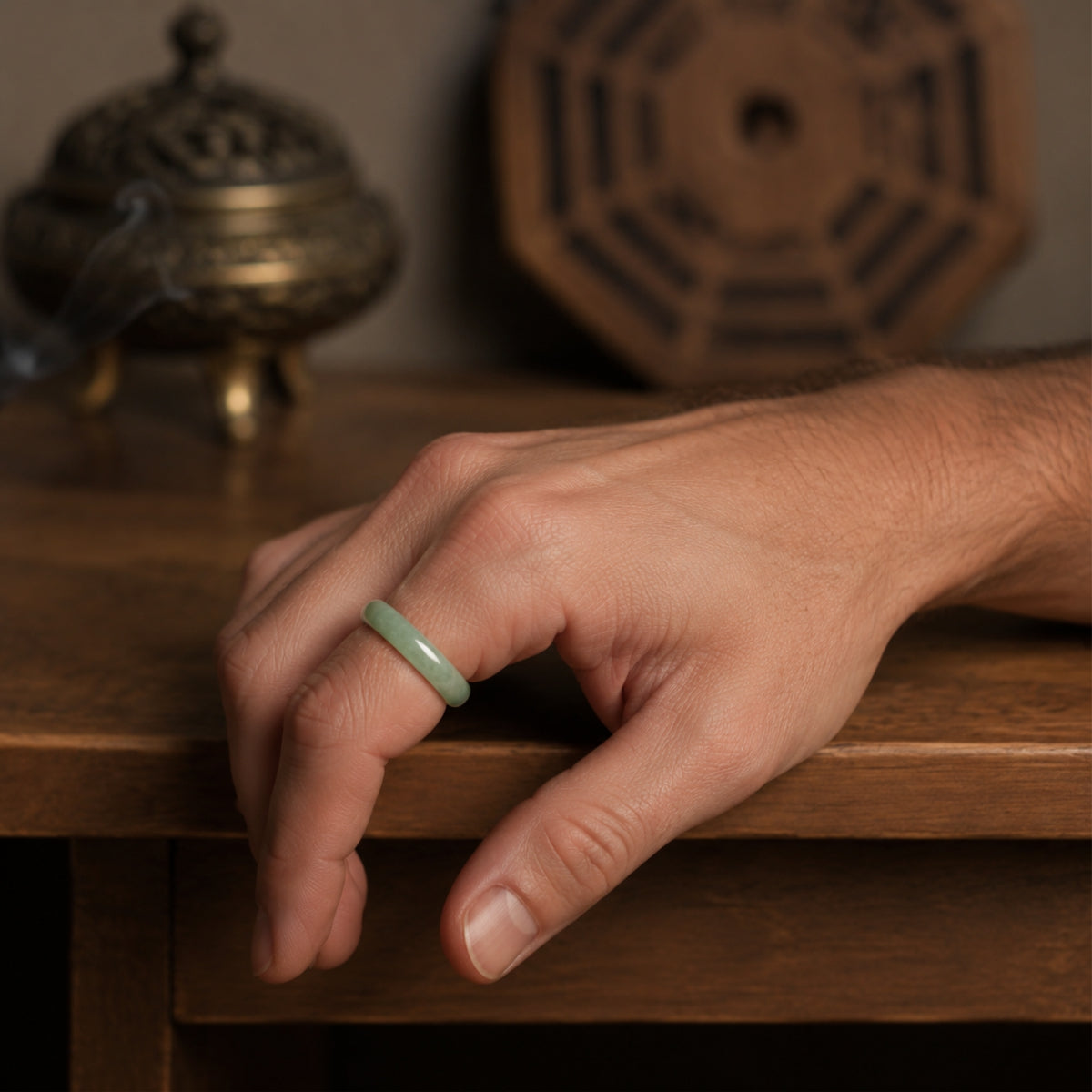 Male hand wearing a natural green jadeite wealth and protection ring.
