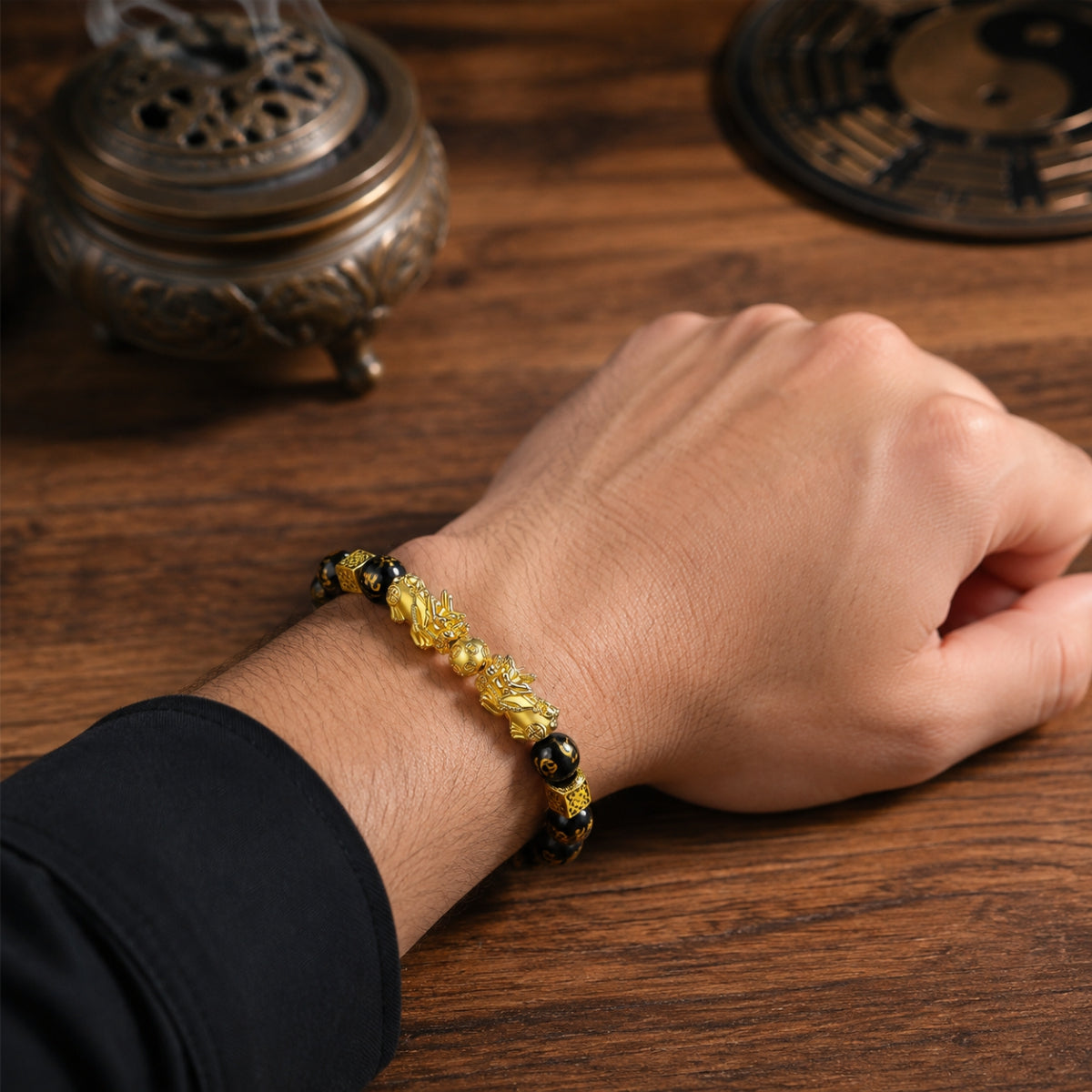 Male wrist wearing a double Pixiu wealth attraction and retention bracelet with black obsidian beads.