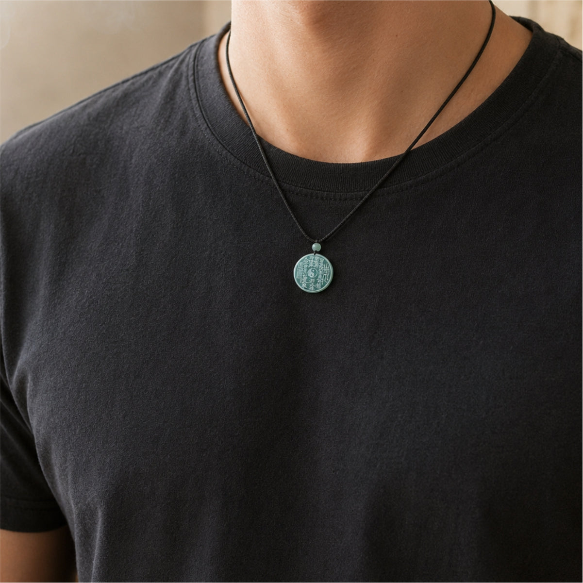 Male wearer with a natural jade Shan Gui coin protection pendant on a black cord.