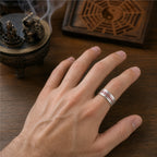 Male hand wearing an adjustable Taoist negative energy protection ring in 925 sterling silver with a red cinnabar protection talisman.