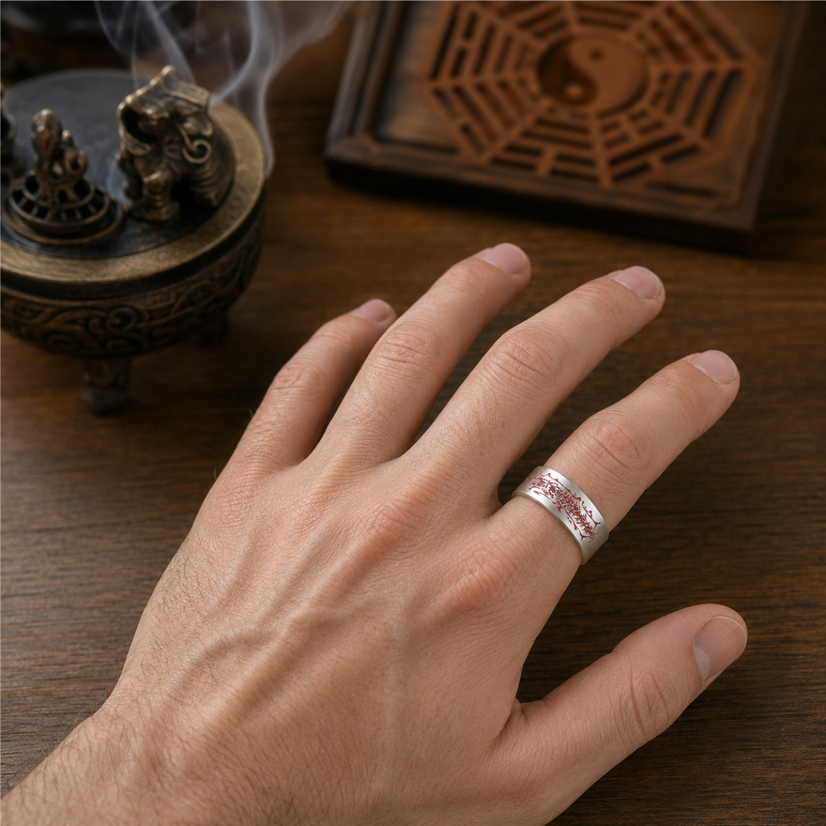 Male hand wearing an adjustable Taoist negative energy protection ring in 925 sterling silver with a red cinnabar protection talisman.