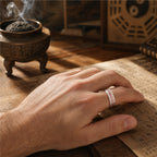 Male hand wearing a handcrafted 925 silver Taoist wealth attraction ring with red cinnabar talisman engraving.