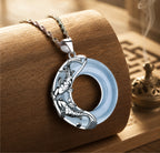 Close-up of a natural pale blue jade koi pendant with sterling silver koi details on a silver chain.