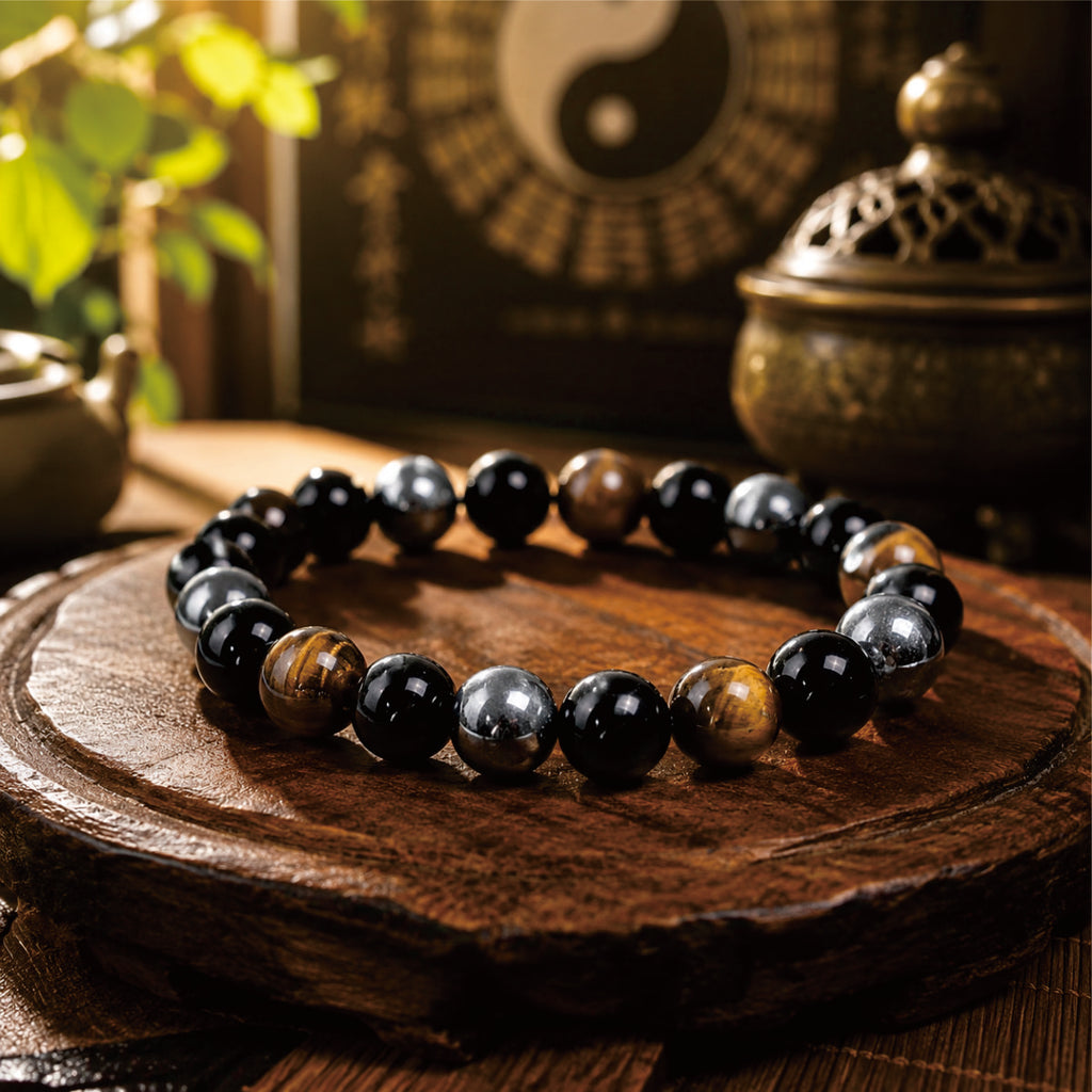 Negative energy protection bracelet with black, silver and tiger eye beads displayed in a Taoist setting