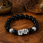 Reverse view of a black obsidian Pixiu wealth guardian bracelet showing detailed silver Pixiu engraving.