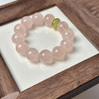 Close-up of a heart healing bracelet with pale pink crystal beads and one green accent bead in a wooden display box