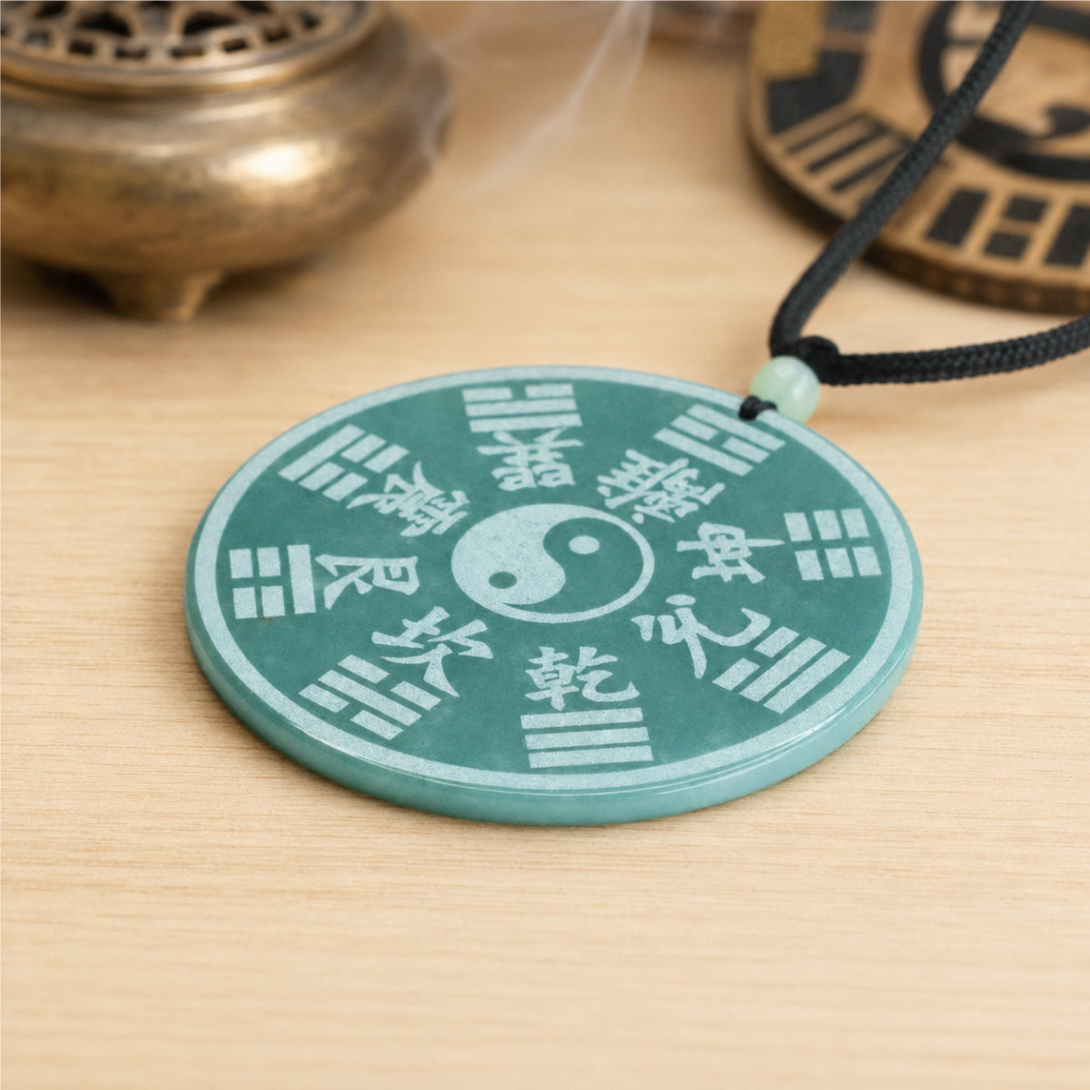 Reverse side of a natural jade Shan Gui protection pendant showing a Yin-Yang symbol and Bagua design.