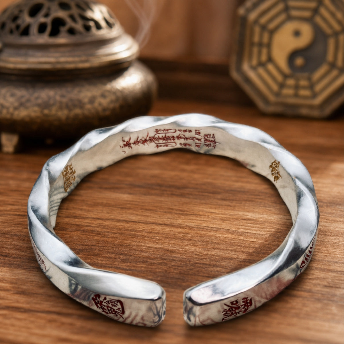 Hand-forged 925 silver Taoist Mobius protection bracelet showing inner fortune talisman engraving and red cinnabar details.