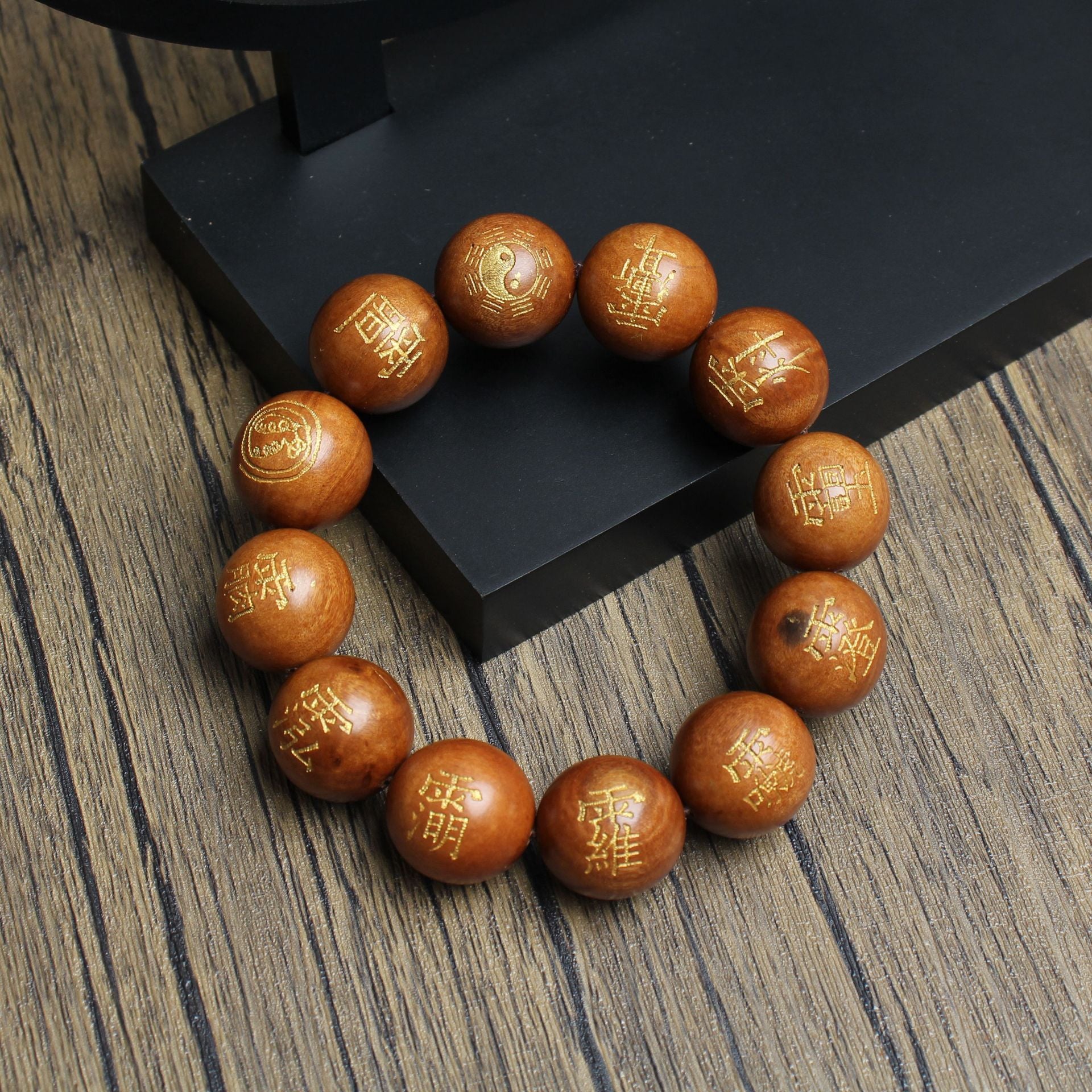 Top view of a thunderstruck wood Five Thunders protection bracelet with gold Taoist talisman engravings