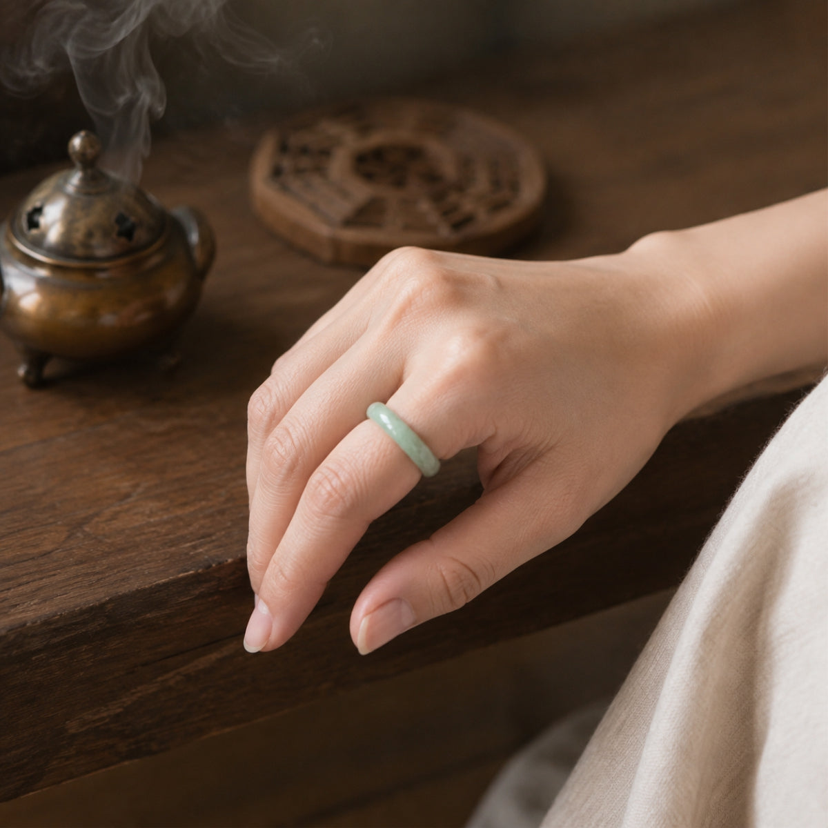 Female hand wearing a natural green jadeite Taoist wealth and protection ring.