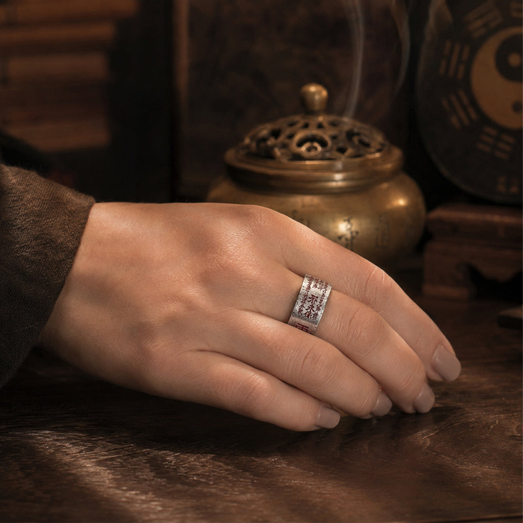 Female hand wearing a Taoist Mountain Ghost Five Thunder protection ring with cinnabar talisman details.