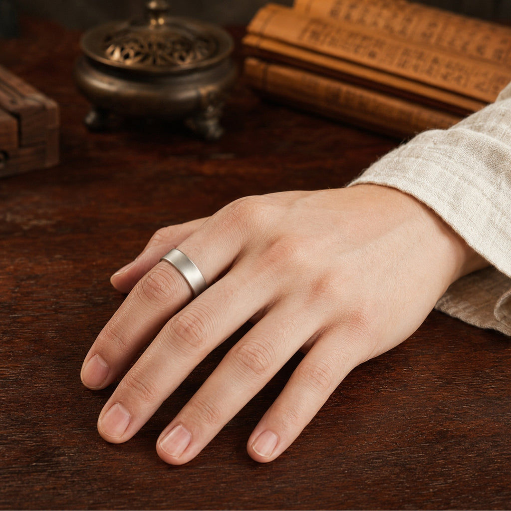 Female hand wearing a 925 silver Taoist four-talisman protection ring on a wooden table beside incense and Daoist scriptures