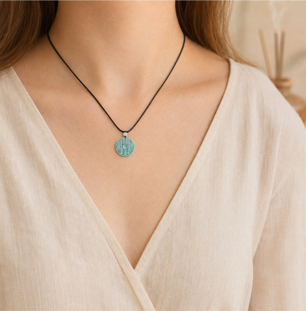 Female wearer with a natural blue-green jade Taoist Shan Gui protection pendant on a black cord.