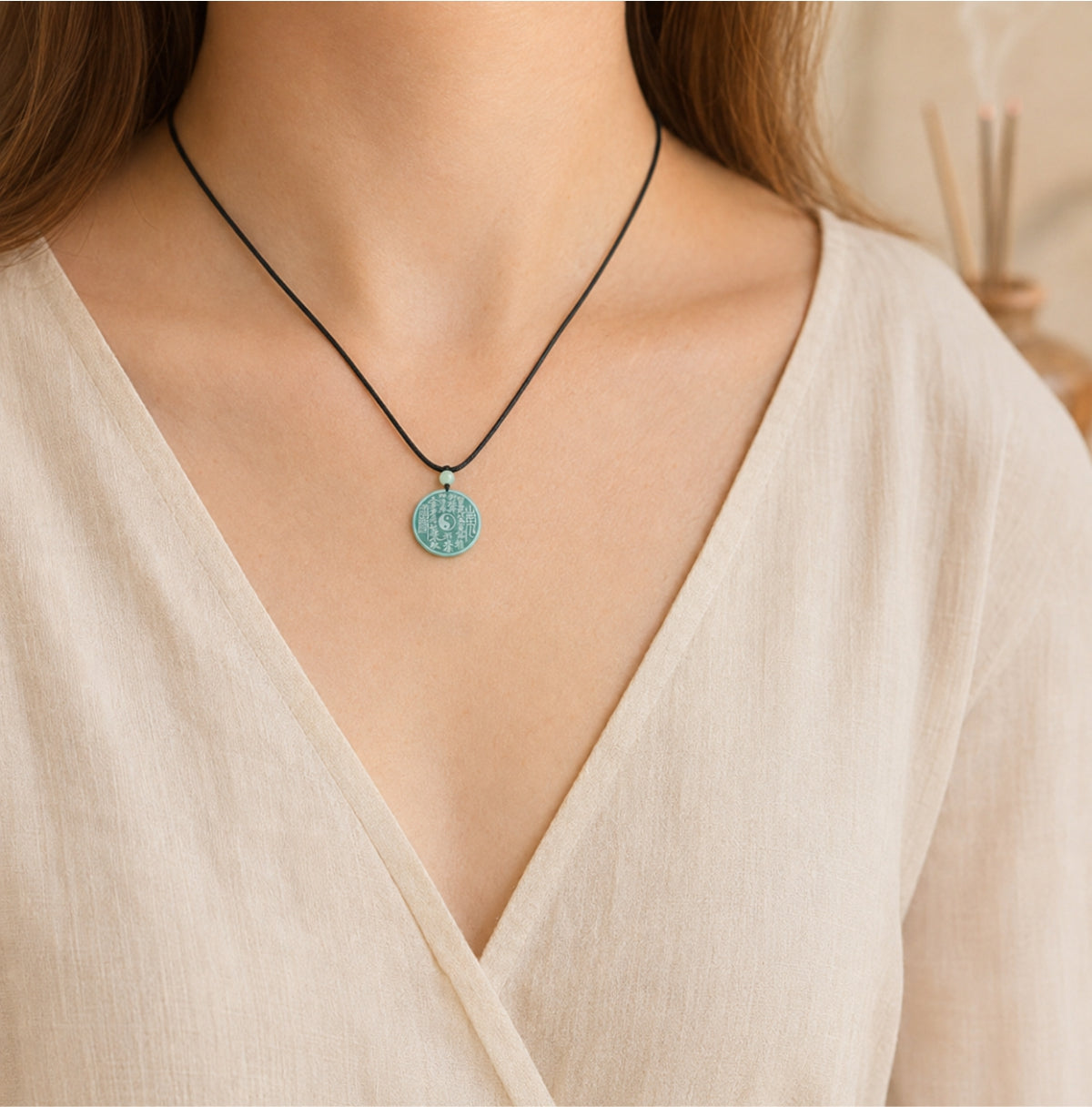 Female wearer with a natural blue-green jade Taoist Shan Gui protection pendant on a black cord.