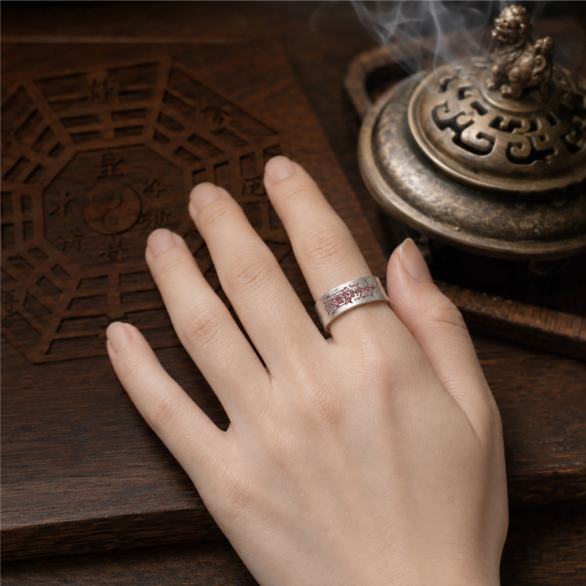 Female hand wearing a handcrafted 925 silver Taoist negative energy protection ring with red cinnabar talisman engraving.