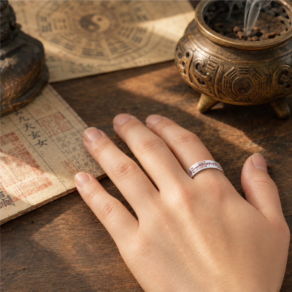 Female hand wearing a 925 silver Taoist wealth attraction ring with red cinnabar wealth talisman details.