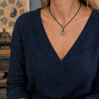 Female model wearing a sterling silver Taoist Yin Yang balance pendant on a black cord necklace.