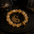 Natural citrine and tiger eye abundance manifestation bracelet with gold crown spacers on Taoist yin yang plate incense burner background Longhu Mountain KaiGuang