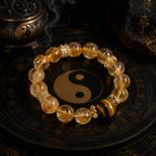 Natural citrine and tiger eye abundance manifestation bracelet with gold crown spacers on Taoist yin yang plate incense burner background Longhu Mountain KaiGuang
