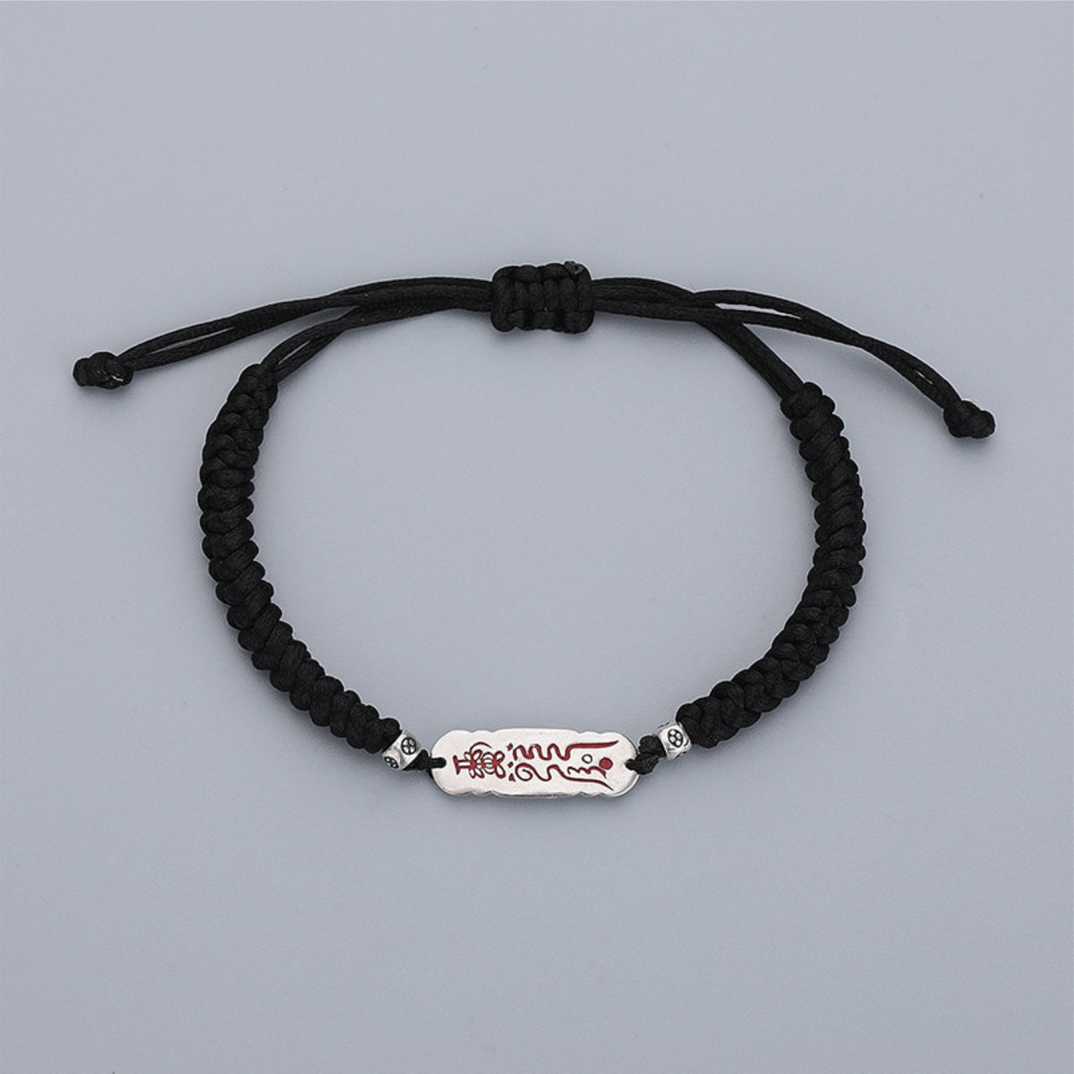 Adjustable black cord bracelet with sliding knot and silver talisman charm, white background
