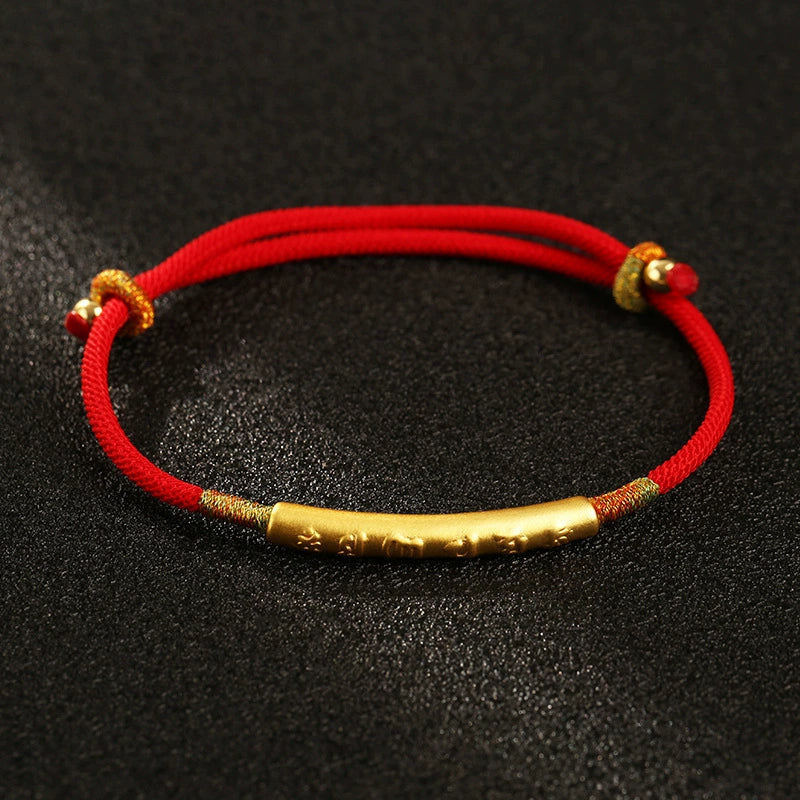 Adjustable red rope protection bracelet with gold talisman tube flat lay black background