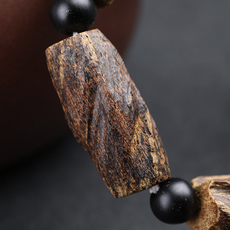 Close-up of aged agarwood raw chunk bead showing natural dark gold wood grain texture Taoist KaiGuang healing energy spiritual bracelet