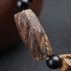 Close-up of aged agarwood raw chunk bead showing natural dark gold wood grain texture Taoist KaiGuang healing energy spiritual bracelet