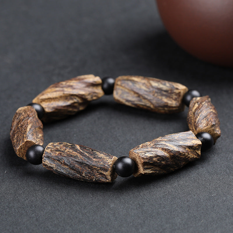 Aged agarwood healing bracelet full circle view on dark background showing raw wood chunk beads with black obsidian spacers Taoist KaiGuang spiritual protection