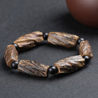 Aged agarwood healing bracelet full circle view on dark background showing raw wood chunk beads with black obsidian spacers Taoist KaiGuang spiritual protection