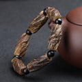 Aged agarwood healing bracelet with raw wood chunks and obsidian spacer beads displayed beside purple clay teapot Taoist KaiGuang meditation protection jewelry