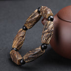 Aged agarwood healing bracelet with raw wood chunks and obsidian spacer beads displayed beside purple clay teapot Taoist KaiGuang meditation protection jewelry