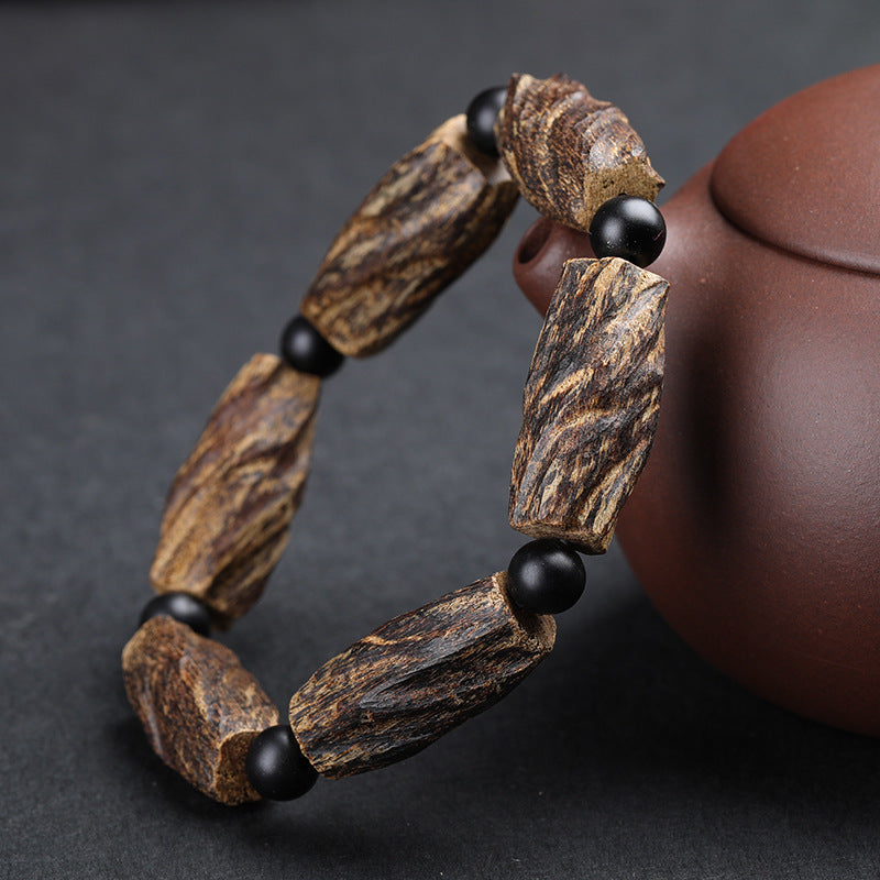 Aged agarwood healing bracelet with raw wood chunks and obsidian spacer beads displayed beside purple clay teapot Taoist KaiGuang meditation protection jewelry