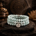 Amazonite 108 bead mala bracelet triple wrap with eye of truth pendant displayed on dark Taoist altar with bronze incense burner and lotus flower meditation anxiety relief