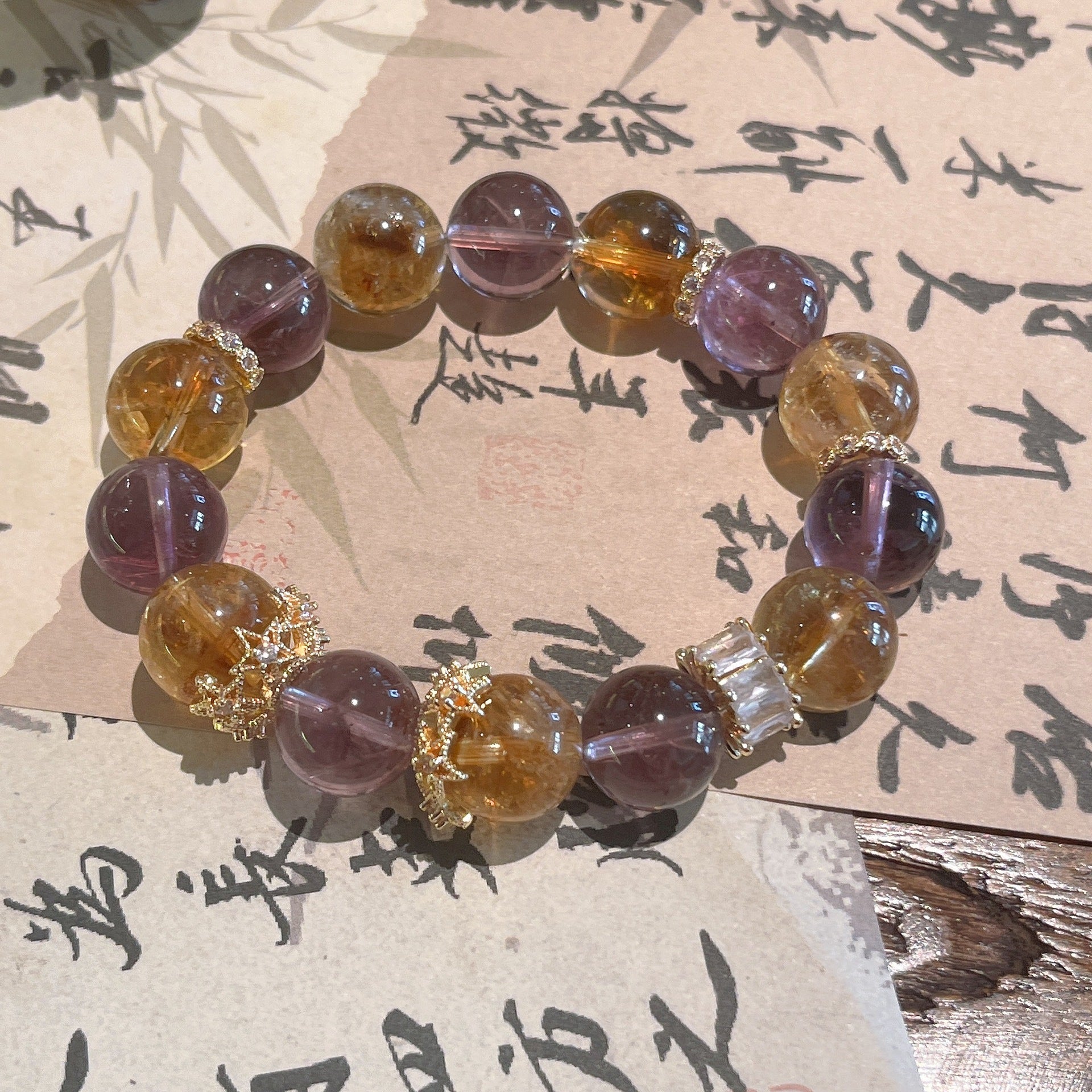 Natural ametrine crystal anxiety relief bracelet with purple amethyst and golden citrine beads gold crown spacers displayed on traditional Chinese calligraphy paper Taoist KaiGuang
