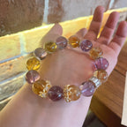 Hand holding natural ametrine crystal anxiety relief bracelet with large purple amethyst and golden citrine beads gold crown spacers warm natural sunlight Taoist KaiGuang