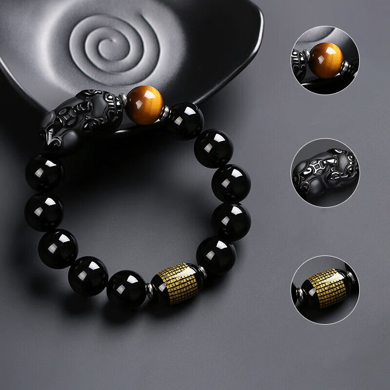 Black obsidian Pixiu bracelet detail showing carved Pixiu guardian tiger eye bead and gold scripture barrel