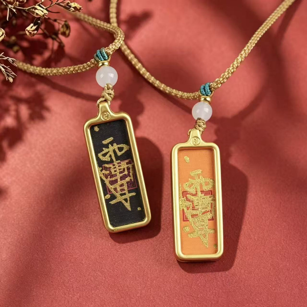 Black and orange Taoist talisman pendants displayed side by side with woven cords and pale round beads.