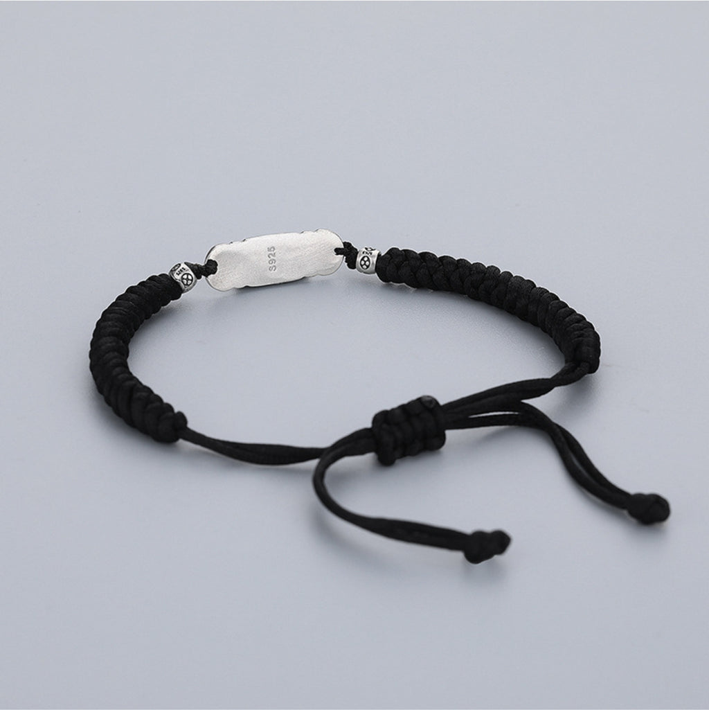 Black string Taoist luck bracelet with engraved S925 silver talisman charm, white background