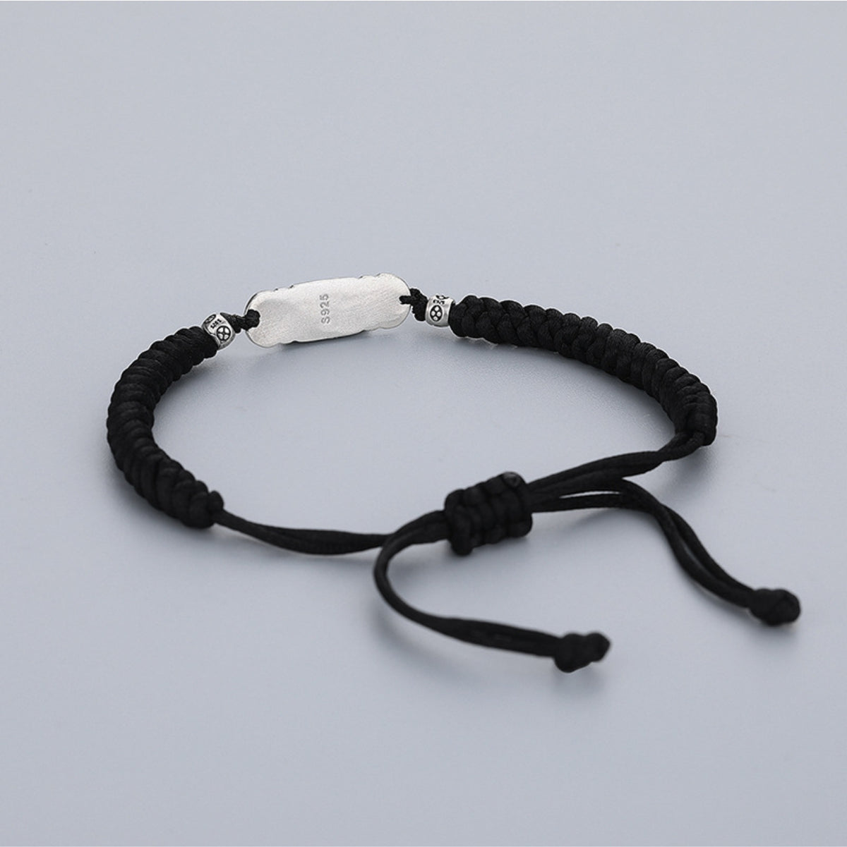 Black string Taoist luck bracelet with engraved S925 silver talisman charm, white background