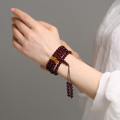 Blood amber 108-bead bracelet worn on wrist for spiritual presence and vitality