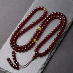Close-up of deep red blood amber prayer beads with golden accents for balanced energy flow.