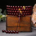 Consecrated Burmese Blood Amber 108 mala beads on a vintage wooden box for vitality.