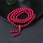Purple cinnabar 108-bead meditation mala on a black matte plate, grounding tool for mindfulness.