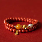 Double layer cinnabar and beeswax bracelet with gold gourd charm resting on red silk — fortune turning jewelry for women